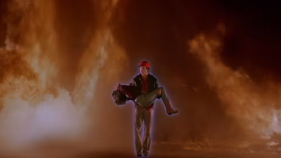 A man carries an unconscious woman through swirling smoke