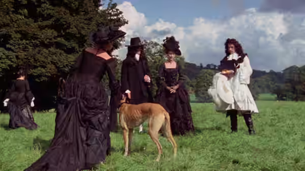 Men and women in dark clothing stand in a field beside a large hound