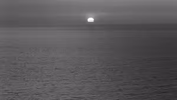 A pale moon hangs above a calm sea