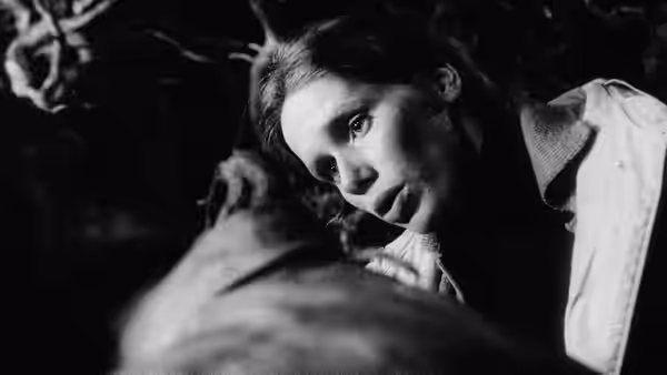Alma Borg (Liv Ullmann) leans over a man lying down