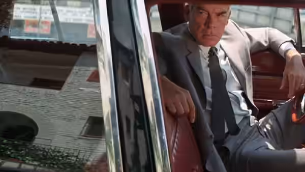 Walker (Lee Marvin) sits in a car doorway, one arm resting on the open door