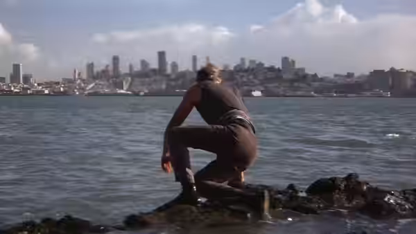 Walker (Lee Marvin) crouches on a rocky shoreline overlooking the city across the water