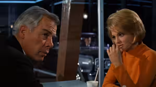 Chris (Angie Dickinson) sits across a table from a gray-haired man