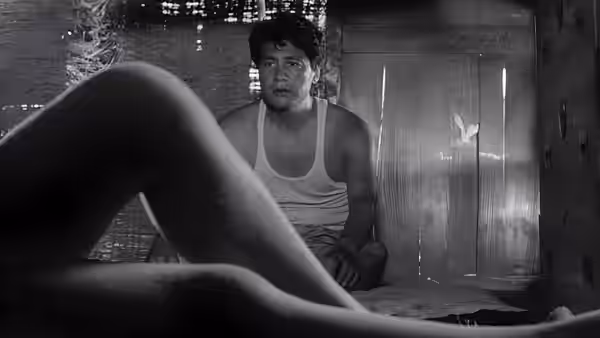 A seated man faces a woman reclining across the foreground inside a room