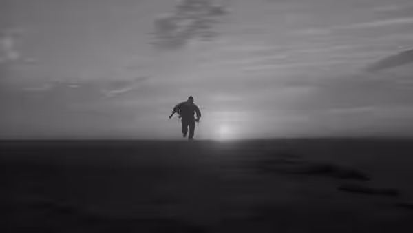 A lone figure walks along a dune ridge toward the low sun