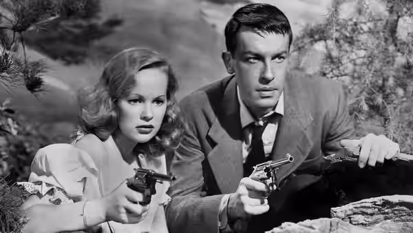 Annie Laurie Starr (Peggy Cummins) and Bart Tare (John Dall) crouch outdoors, holding pistols