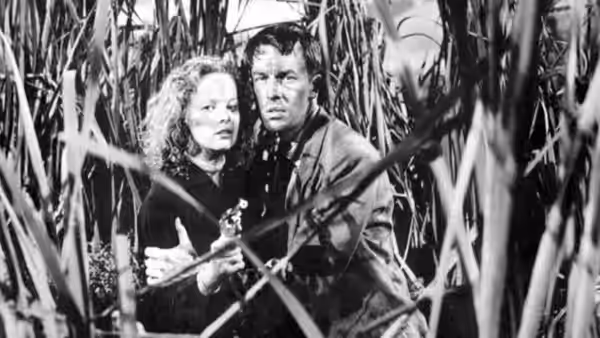 Annie Laurie Starr (Peggy Cummins) and Bart Tare (John Dall) hide among tall reeds