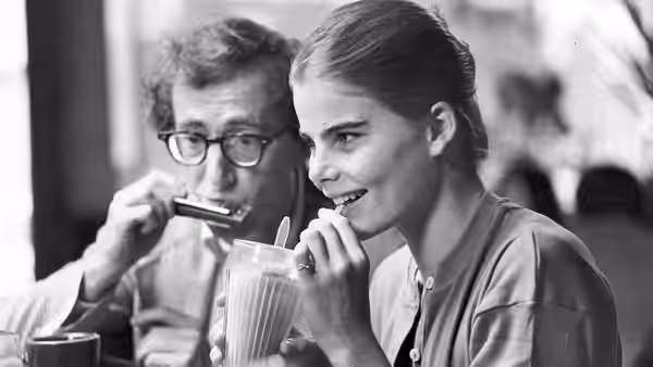 Isaac Davis (Woody Allen) plays harmonica beside Tracy (Mariel Hemingway) at a table