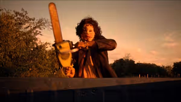 Man gripping a running chainsaw on the back of a truck at dusk