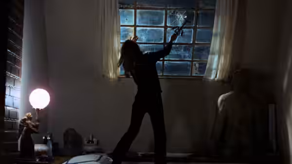 A silhouetted woman raises an arm beside a window as another figure sits nearby