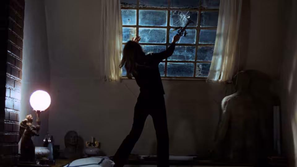 A silhouetted woman raises an arm beside a window as another figure sits nearby