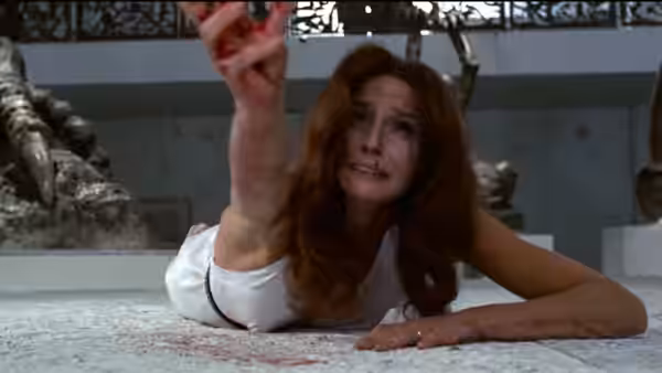 A woman lies on the floor, reaching upward beneath a glass ceiling