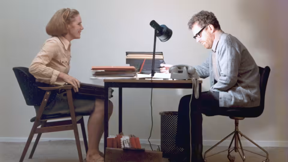 Marianne (Liv Ullmann) and Johan (Erland Josephson) talk across an office desk