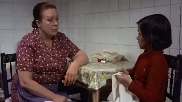 Rosa (Florinda Chico Martín-Mora) talks with Ana (Ana Torrent) at a tiled kitchen table