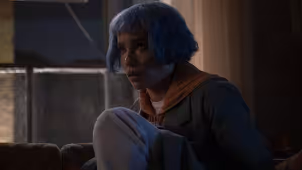 Angela Childs (Zoë Kravitz) seated on a couch looking concerned