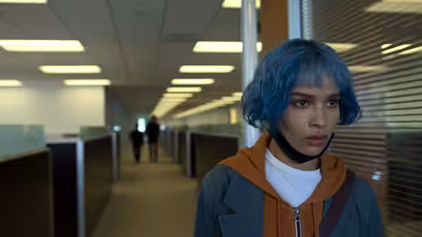 Angela Childs (Zoë Kravitz) standing in an empty office corridor