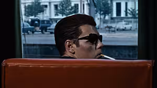 Chas (James Fox) smokes a cigarette while looking out a car window