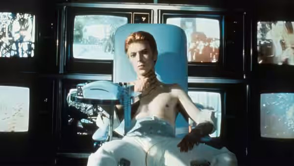 Thomas Jerome Newton (David Bowie) seated shirtless in a medical chair with tubes attached
