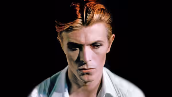 Thomas Jerome Newton (David Bowie) with red hair looking down in close-up