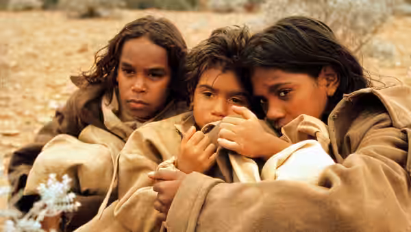 Molly Craig and her companions huddle together, wrapped in blankets on the ground