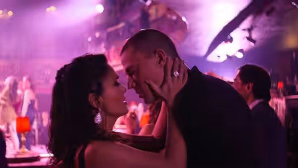 a woman holds a man's face as they stand close together in a nightclub