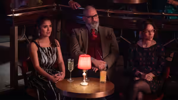 three people sit together at a small table with drinks in a lounge
