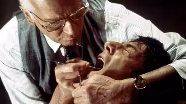 Dr. Christian Szell (Laurence Olivier) leaning over Thomas 'Babe' Levy (Dustin Hoffman) with dental tools in his mouth
