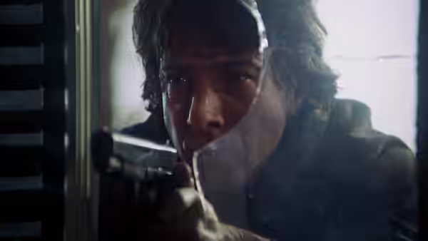 Thomas 'Babe' Levy (Dustin Hoffman) gripping a pistol near cracked glass with a focused stare