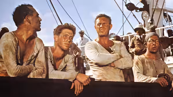 Papillon (Steve McQueen) and prisoners standing on the deck of a ship
