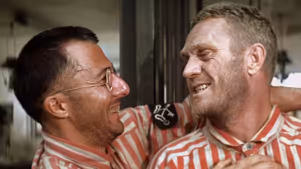 Papillon (Steve McQueen) and Louis Dega (Dustin Hoffman) laughing in striped uniforms
