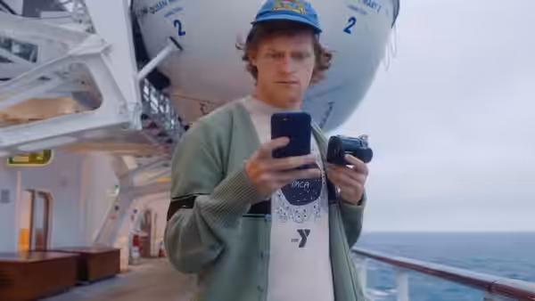 Tyler Hughes (Lucas Hedges) checking phones on a cruise ship deck