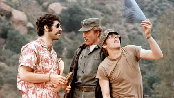 Trapper John (Elliott Gould) standing with Lt. Col. Henry Blake (Roger Bowen) and Radar O'Reilly (Gary Burghoff)