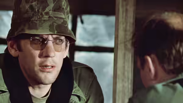 Close-up of a soldier in camouflage hat and glasses speaking inside a tent