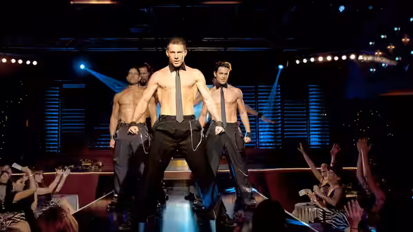 Mike (Channing Tatum) dancing shirtless with other performers on a nightclub stage
