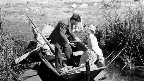 The Man (George O'Brien) and the Wife (Janet Gaynor) balance in a small boat among reeds