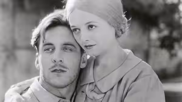 A man and woman sit close with her head resting against his shoulder