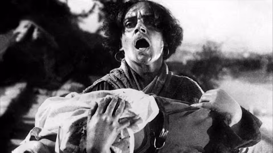 A woman cries out while cradling a wounded sailor in her arms