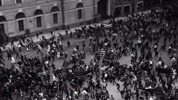 People scatter across a city square as soldiers advance beside the buildings