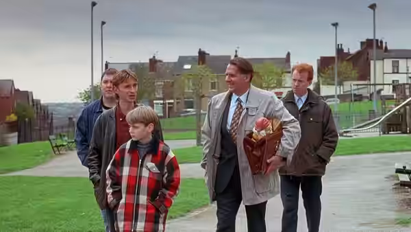 Gerald (Tom Wilkinson) walks with a boy and three men across grass