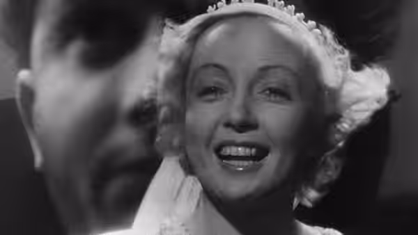 A smiling woman in a white head covering fills the frame