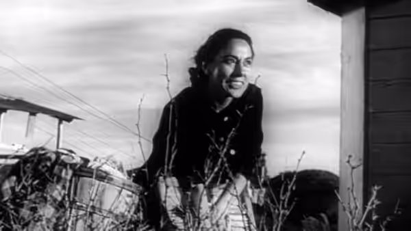 Esperanza Quintero (Rosaura Revueltas) smiles while tending plants outside a building