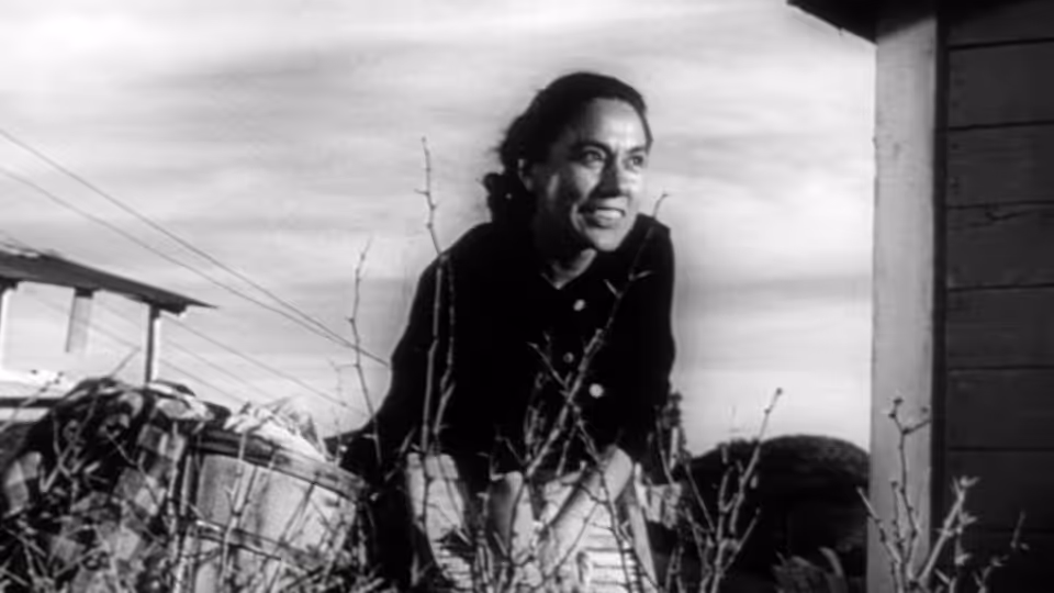 Esperanza Quintero (Rosaura Revueltas) smiles while tending plants outside a building