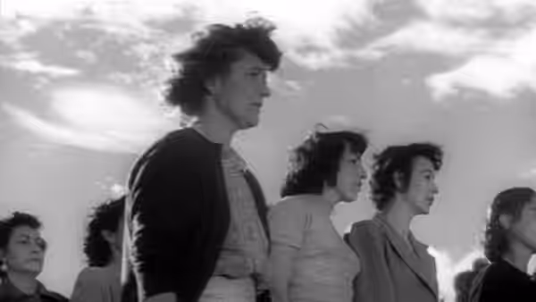 Women walk together outdoors beneath a cloudy sky