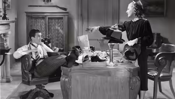 Jefferson Smith (James Stewart) reclining as Clarissa Saunders (Jean Arthur) gestures