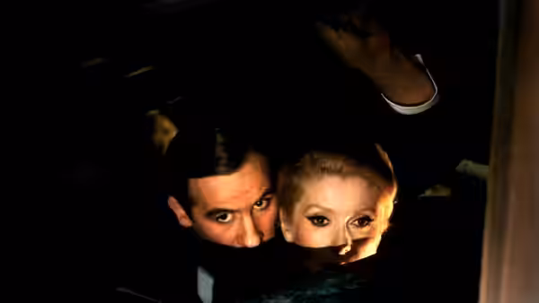 Marion Steiner (Catherine Deneuve) and Bernard Granger (Gérard Depardieu) peer from a dark hiding place