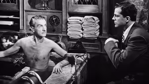 Mark McPherson (Dana Andrews) sits shirtless while talking with Shelby Carpenter