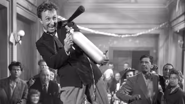 A suited man raises a horn as guests watch inside a crowded hall