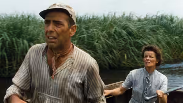 Charlie Allnut (Humphrey Bogart) steering the boat while Rose Sayer (Katharine Hepburn) watches