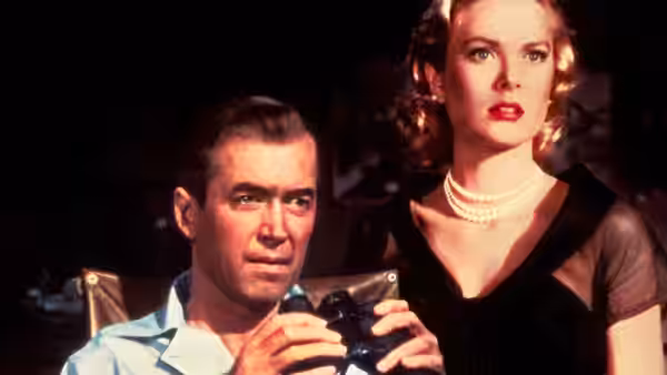 L.B. Jefferies (James Stewart) holding binoculars with Lisa Fremont (Grace Kelly) behind him