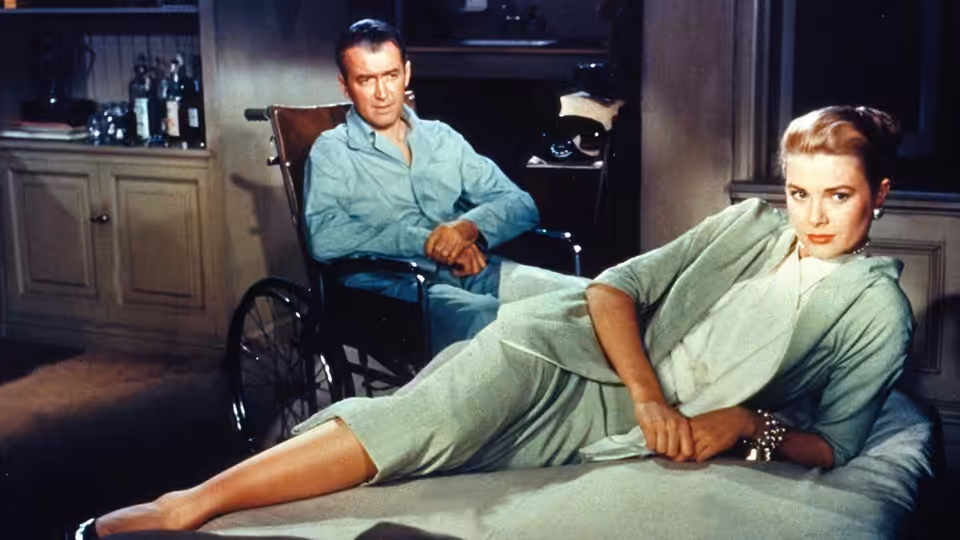 L.B. Jefferies (James Stewart) in wheelchair beside Lisa Fremont (Grace Kelly) on the bed